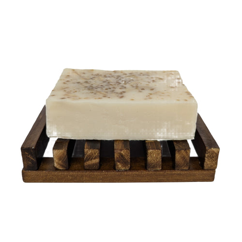 Bar of soap on a wooden soap dish against a white background