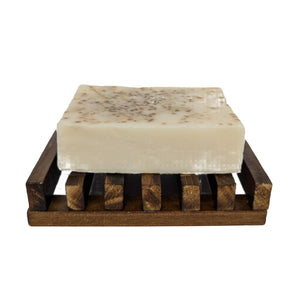 Bar of soap on a wooden soap dish against a white background